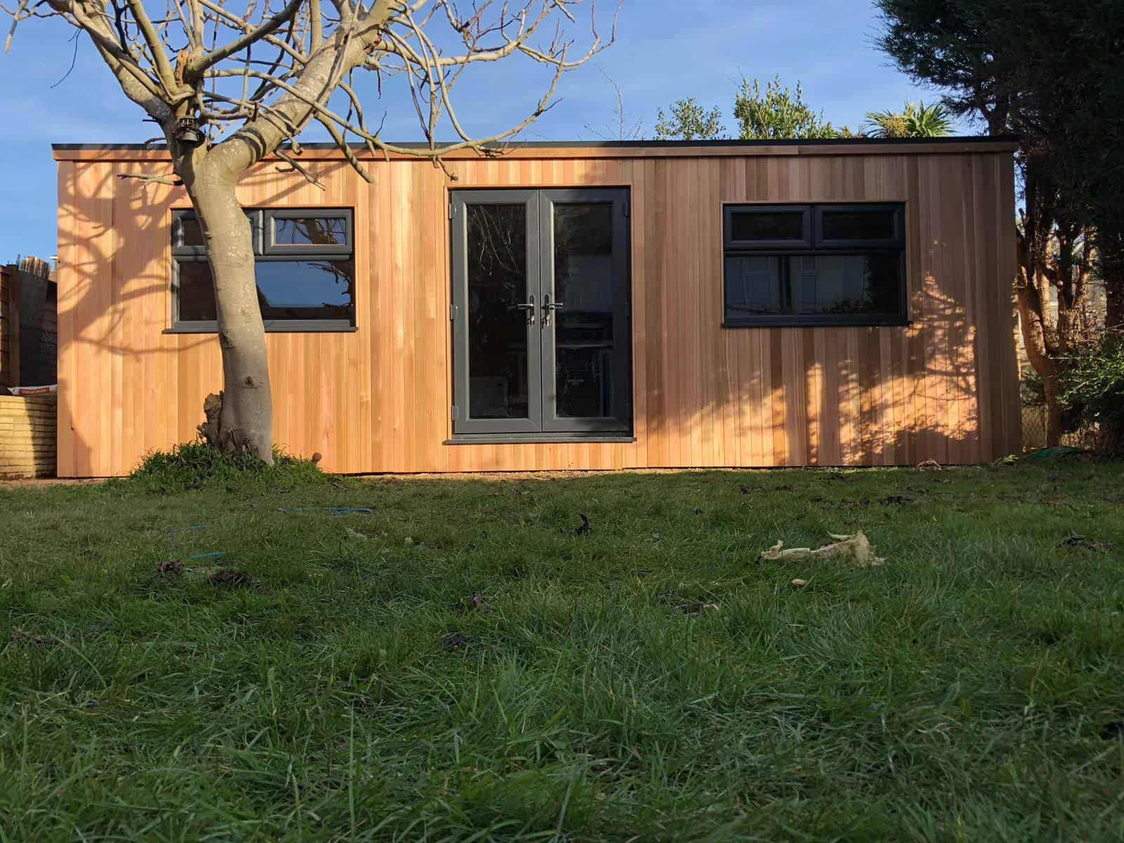 Cedar clad man cave, sat at the bottom of a garden. 1.5m french doors are fit central on the building with two windows sat either side keeping the building looking symmetrical and stylish.