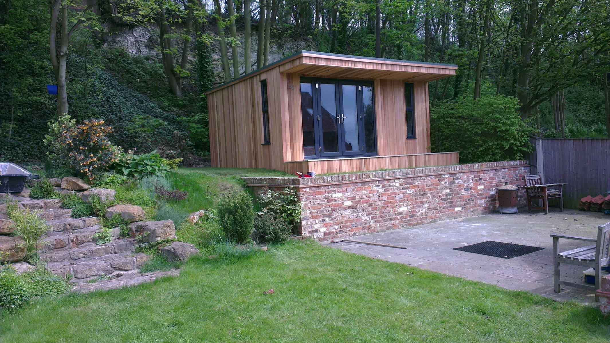 Garden cabin set behind a brick retaining wall